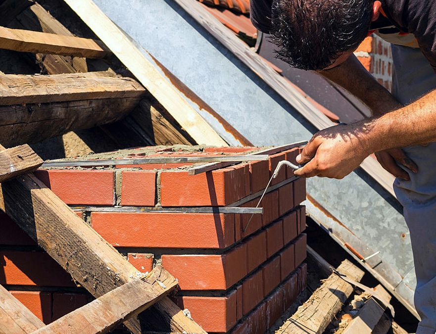Mason laying fresh brick courses on a Staten Island chimney rebuild
